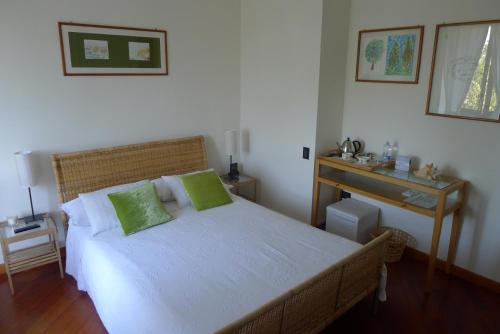 a bedroom with a bed with green pillows and a desk at B&b La corte dei Gelsomini in Ponteranica