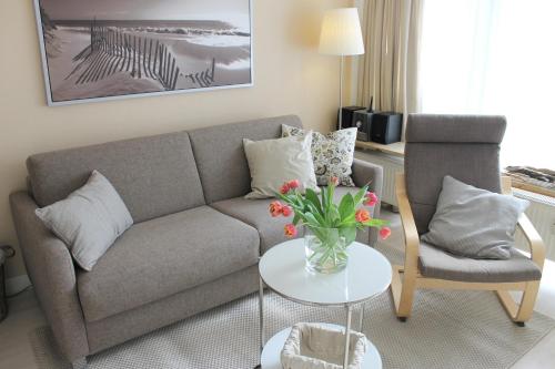 een woonkamer met een bank, een tafel en een stoel bij Haus Baltic - Whg 23 - NEU inkl Saisonstrandkorb! in Grömitz
