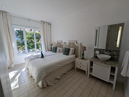 a white bedroom with a large bed and a sink at Maison La Plage by Simply-Seychelles in Eden Island