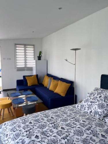 een kamer met een bed en een blauwe bank bij Ma chaumière santenoise in Santeny