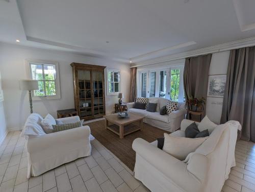 a living room with white furniture and windows at Maison La Plage by Simply-Seychelles in Eden Island