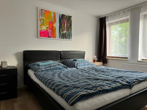a bed with a blue comforter in a bedroom at Pension Sachseneck in Heidenau