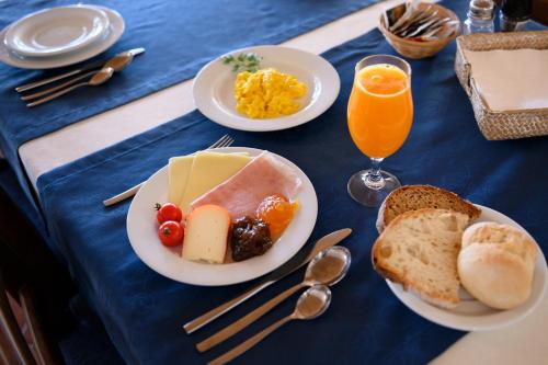 a blue table topped with plates of food and orange juice at Falésias da Arrifana in Praia da Arrifana