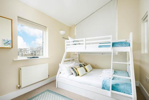 ein weißes Etagenbett in einem Zimmer mit Fenster in der Unterkunft Falcon House CW73 Lower Mill Estate Cotswolds in Somerford Keynes