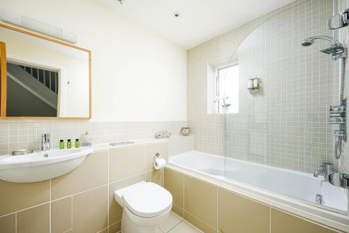 a bathroom with a tub and a toilet and a sink at Falcon House CW73 Lower Mill Estate Cotswolds in Somerford Keynes