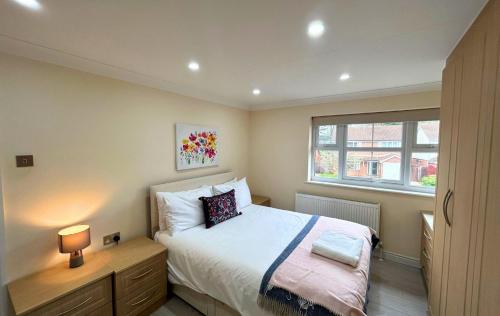 niewielka sypialnia z łóżkiem i oknem w obiekcie Addlestone Stylish Spacious Three Bedroom House w mieście Addlestone