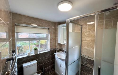 een badkamer met een toilet, een wastafel en een raam bij Addlestone Stylish Spacious Three Bedroom House in Addlestone