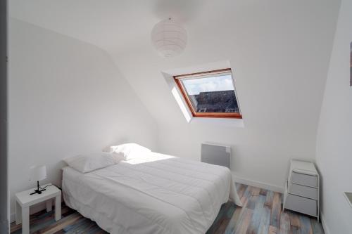 een witte slaapkamer met een bed en een raam bij Ti Louarn - Maison à 2 km de la plage in Fouesnant