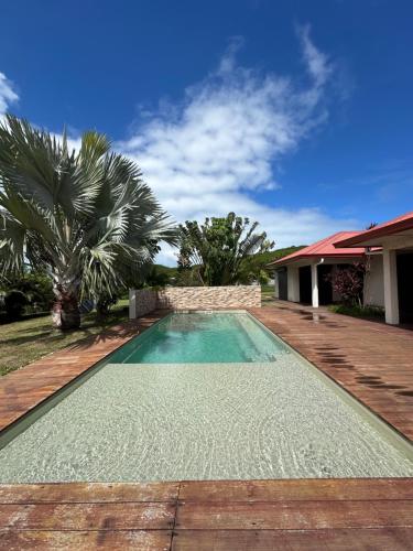 una piscina en un patio con una casa en Grande Villa Familiale avec piscine et Accès Privé à la Plage en Païta
