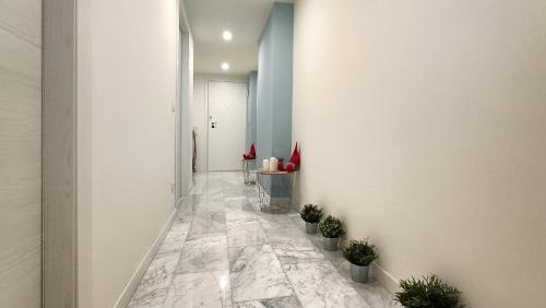 un couloir avec un sol en marbre, des murs blancs et des plantes en pot dans l'établissement SAHI - Via Dei Ciclamini MM1 Primaticcio, Stadio San Siro, ospedale San Carlo, à Milan