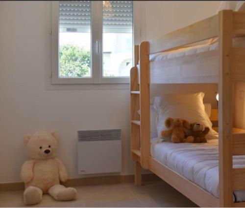 2 ours en peluche assis sur le sol dans une chambre dans l'établissement Appart. en Corse t3 bord de mer et piscine. N 143, à Linguizzetta