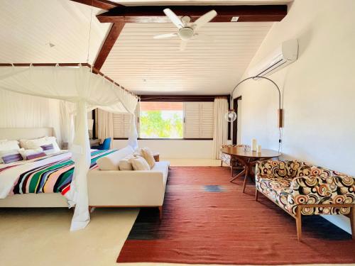 a bedroom with a bed and a couch and a table at Casa Canada Bahia in Praia do Espelho