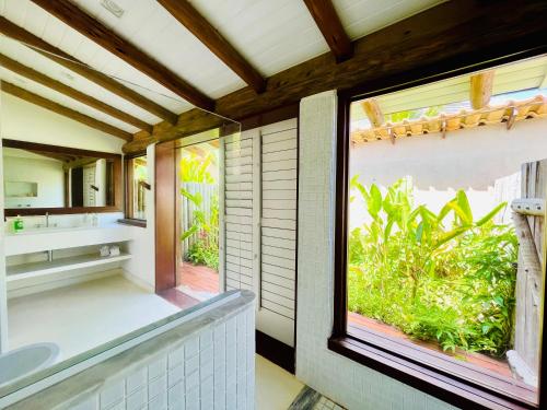 baño con ventana grande con vistas al jardín en Casa Canada Bahia en Praia do Espelho