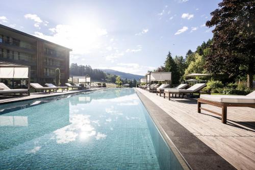 einen Pool mit Liegestühlen und ein Gebäude in der Unterkunft Alpine Spa Resort Viktoria in Avelengo