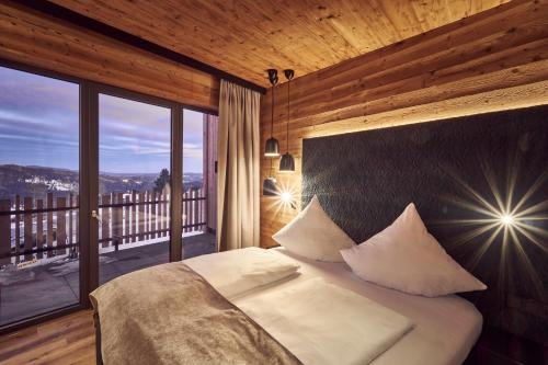 a bedroom with a large bed with a large window at Hunderesort Waldeck - 4 Sterne Urlaub mit Hund in Philippsreut