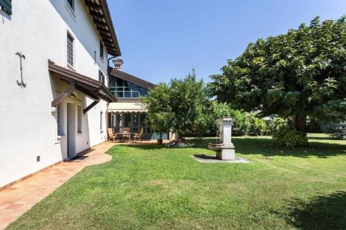 een tuin voor een wit gebouw met een boom bij Ferienhaus in Aquileia mit Großem Garten in Aquiléia