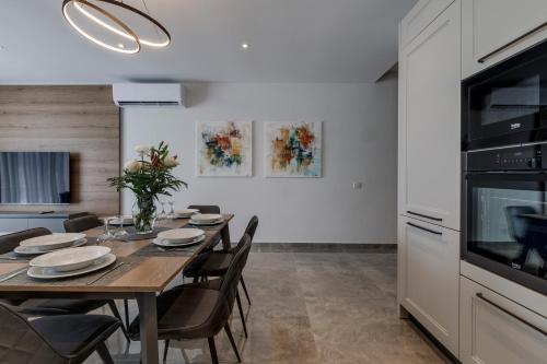 a kitchen and dining room with a wooden table and chairs at Lovely Penthouse in Mellieha-seaview by Homely in Mellieħa