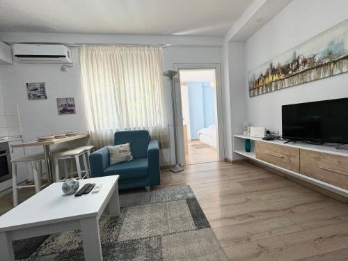 - un salon avec une télévision, un canapé et une table dans l'établissement Apartment in the New Bazaar of Tirana - Hana Blu, à Tirana