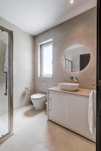 a bathroom with a sink and a toilet and a mirror at Lovely Penthouse in Mellieha-seaview by Homely in Mellieħa