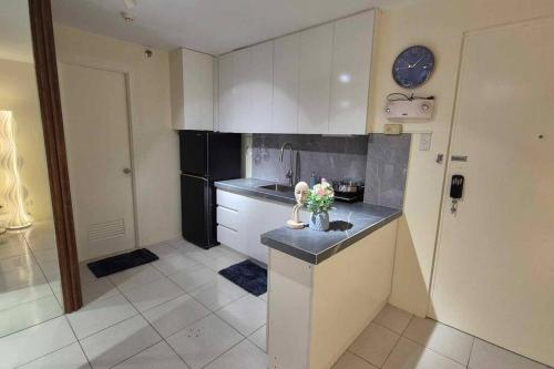 Una cocina con gabinetes blancos y una encimera negra. en Muji Style Condo with Parking, en Manila