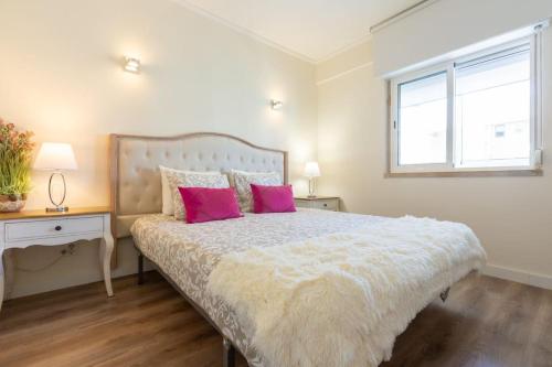 a bedroom with a bed with pink pillows and a window at beachome4u4 / Carcavelos beach in Parede