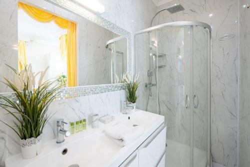 een witte badkamer met een wastafel en een douche bij Suite Soleil - Paris à 10 min - Apt d'exception in Deuil-la-Barre