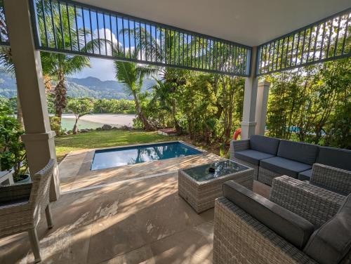 a patio with a pool and a couch and chairs at Maison La Plage by Simply-Seychelles in Eden Island
