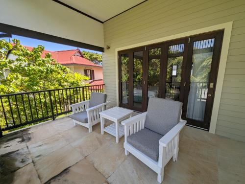 a porch with two chairs and a table on it at Maison La Plage by Simply-Seychelles in Eden Island