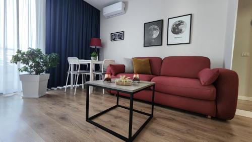 a living room with a red couch and a table at 3S Apartments -Sea-Sun-Sky- in Sarandë
