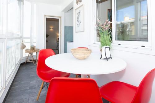 a dining room with a white table and red chairs at beachome4u4 / Carcavelos beach in Parede