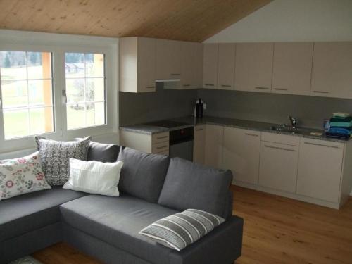 ein Wohnzimmer mit einem Sofa und einer Küche in der Unterkunft Ballmoos Ferienwohnung in Gais