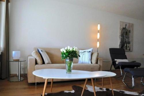 uma sala de estar com um sofá e uma mesa com flores em Ferienwohnung Chäserruggblick mit Charme em Unterwasser