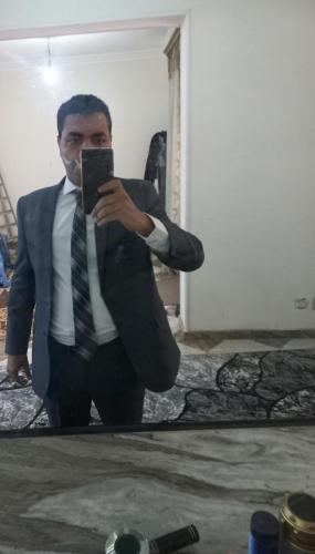 un hombre con traje y corbata tomando una foto en un espejo en Skymoon, en El Cairo