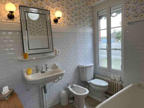 La salle de bains est pourvue d'un lavabo, de toilettes et d'un miroir. dans l'établissement Villa Les Myosotis, à Dinard