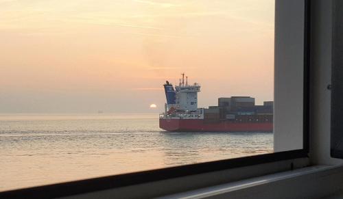 a container ship in the water at sunset at Wohnung in Vlissingen mit Terrasse und Meerblick in Vlissingen