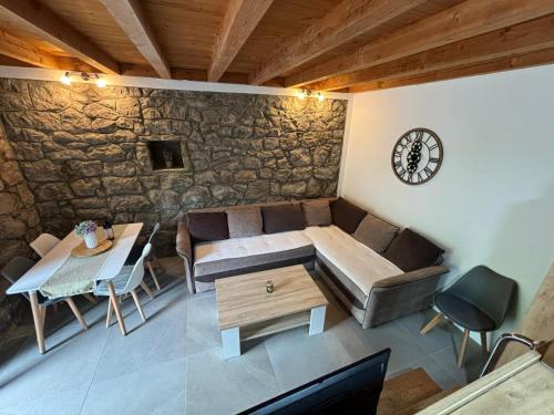 uma sala de estar com um sofá, uma mesa e um relógio em Bay House Kakrc em Tivat