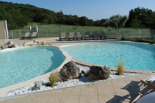 une grande piscine avec des chaises et des rochers dans une cour dans l'établissement Villa Adhémar Gîte Les Lauriers, à La Garde-Adhémar