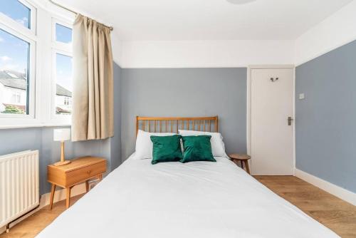 1 dormitorio con cama blanca y almohadas verdes en Pass the Keys Spacious Family Home in London, en Londres