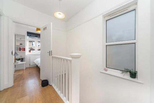 Pasillo blanco con ventana y dormitorio en Pass the Keys Spacious Family Home in London, en Londres