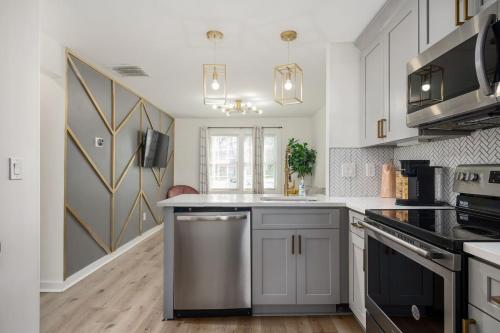 a kitchen with white cabinets and a stainless steel dishwasher at Chic 1BD in Sylvan Hills Near Southside Beltline in Atlanta