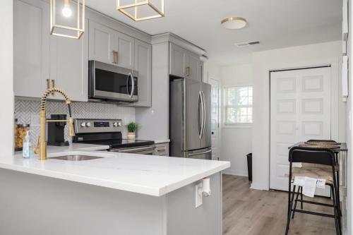 a white kitchen with a sink and a refrigerator at Chic 1BD in Sylvan Hills Near Southside Beltline in Atlanta