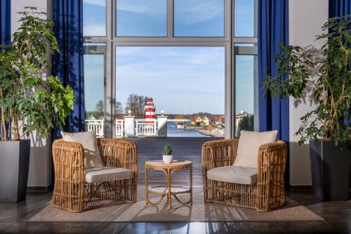 Zimmer mit 2 Stühlen, einem Tisch und einem Fenster in der Unterkunft Precise Resort Hafendorf Rheinsberg in Rheinsberg