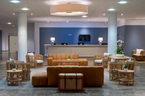 a waiting room with couches and tables and chairs at Precise Resort Hafendorf Rheinsberg in Rheinsberg