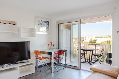 sala de estar con TV y mesa con sillas en Mimosas furnished flat, en Antibes