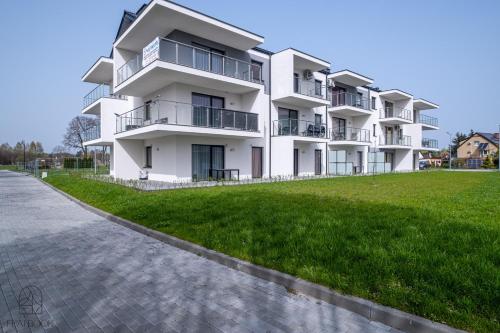 a white apartment building with a green lawn in front of it at Flatbook Apartamenty - Sztutowo Baltic Twins II in Sztutowo