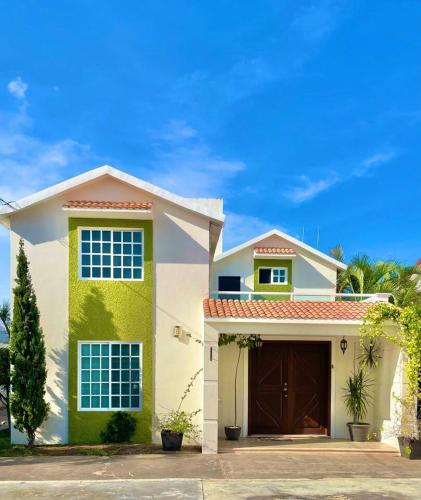 une maison blanche et verte avec un garage dans l'établissement Casa Coccoloba, Chetumal, Quintana Roo, à Chetumal