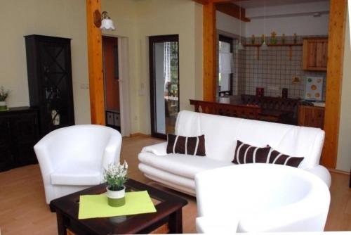 een woonkamer met twee witte banken en een tafel bij Ferienwohnung in Leuenberg mit Garten und Grill in Werneuchen