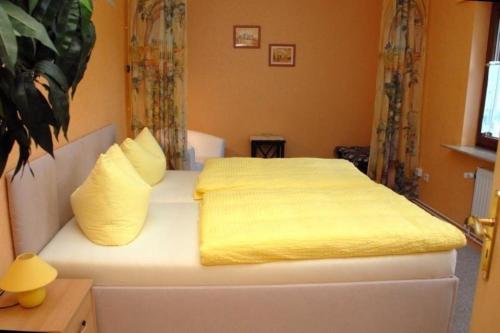 - un lit avec des draps et des oreillers jaunes dans l'établissement Ferienwohnung in Leuenberg mit Garten und Grill, à Werneuchen