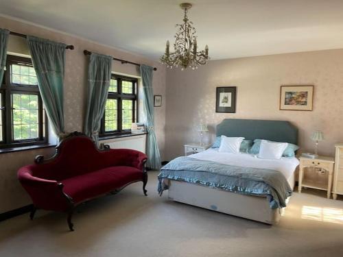 a bedroom with a bed and a red chair at Beautiful Stratford-On-Avon House, suits 14 - 15 in Shottery