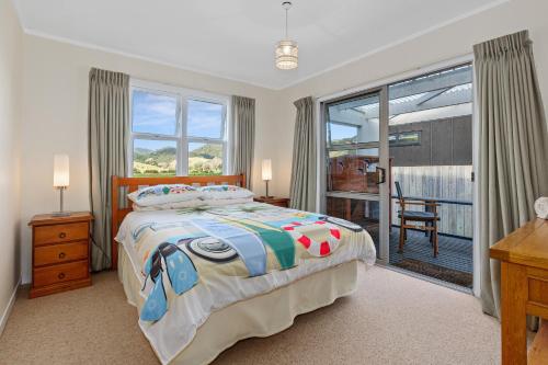 a bedroom with a bed and a desk and a window at Teal Bay Treasure - Teal Bay Holiday Home in Whangaruru North